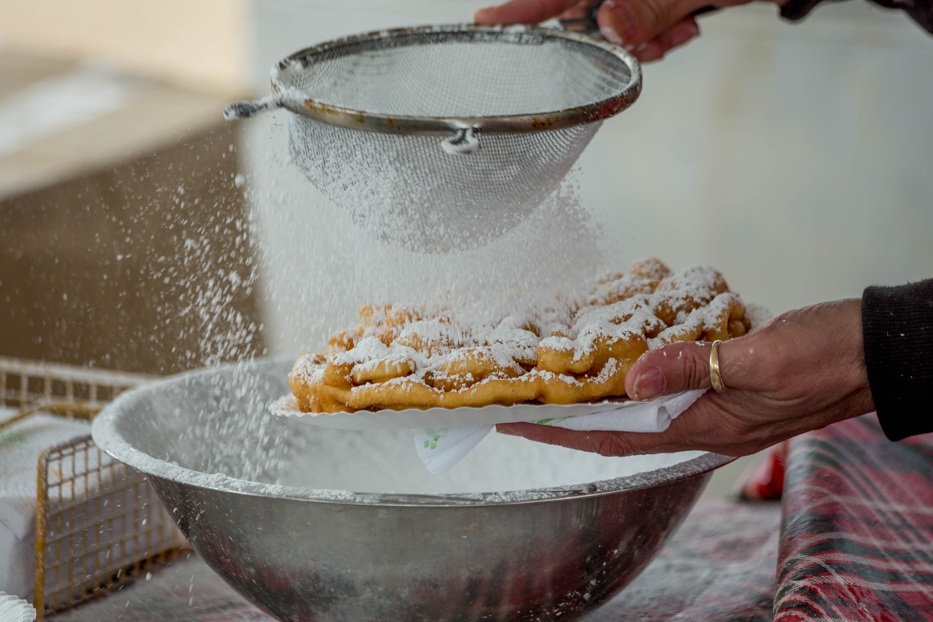 Powdered sugar being sprinkled on a funnel cake