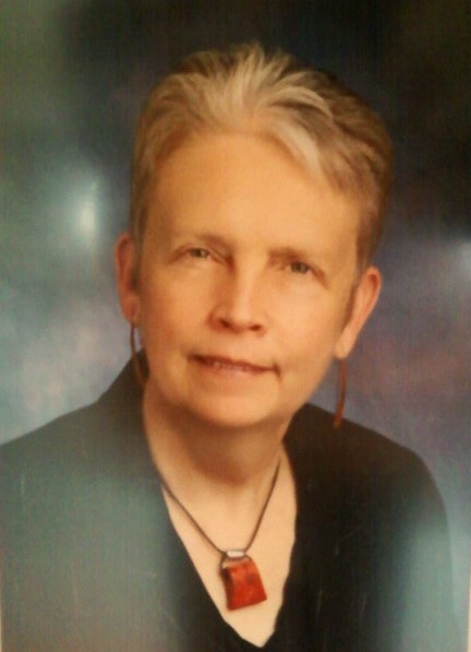 A woman with short hair wearing a black blouse and red necklace