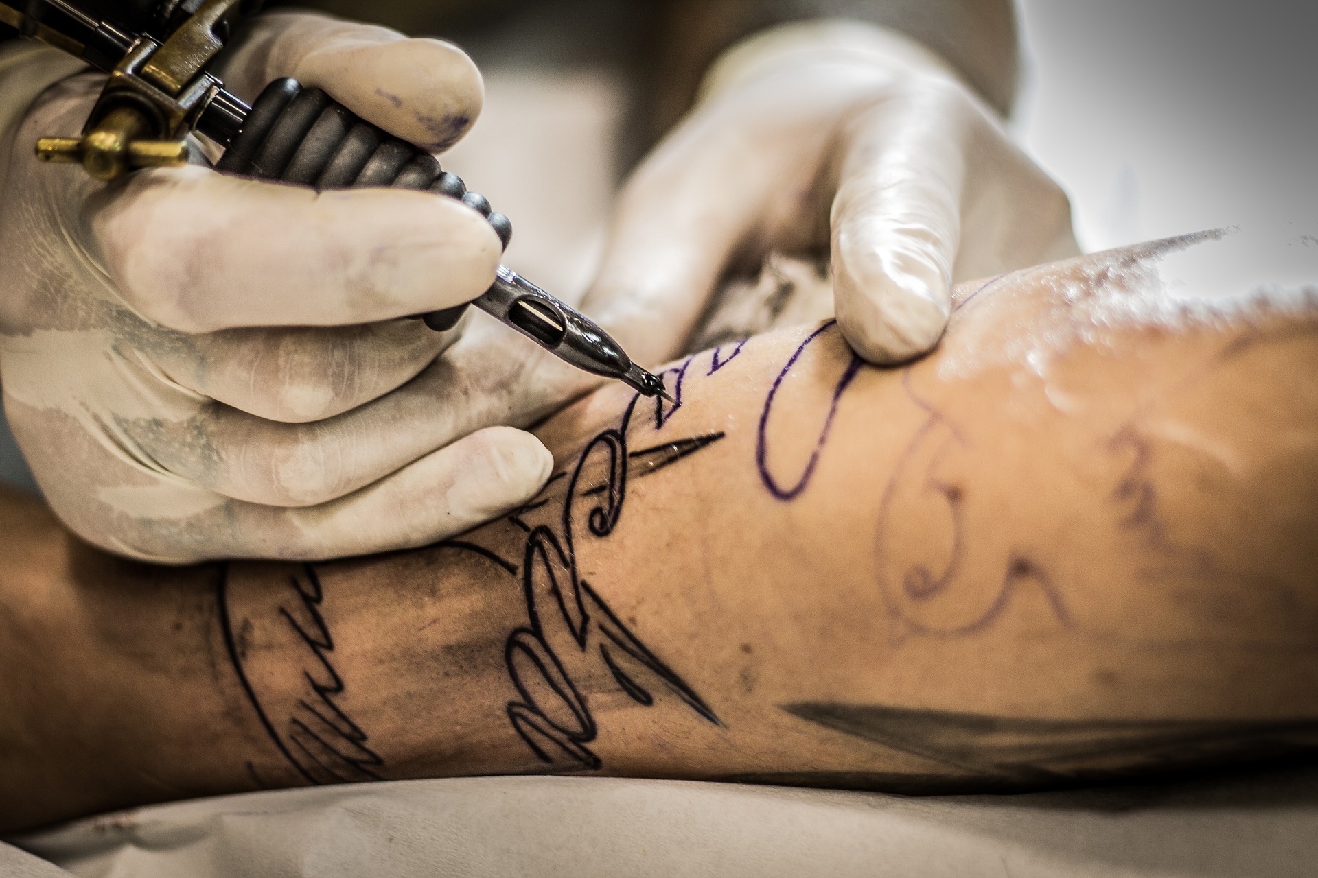 Tattoo artist wearing gloves giving tattoo 