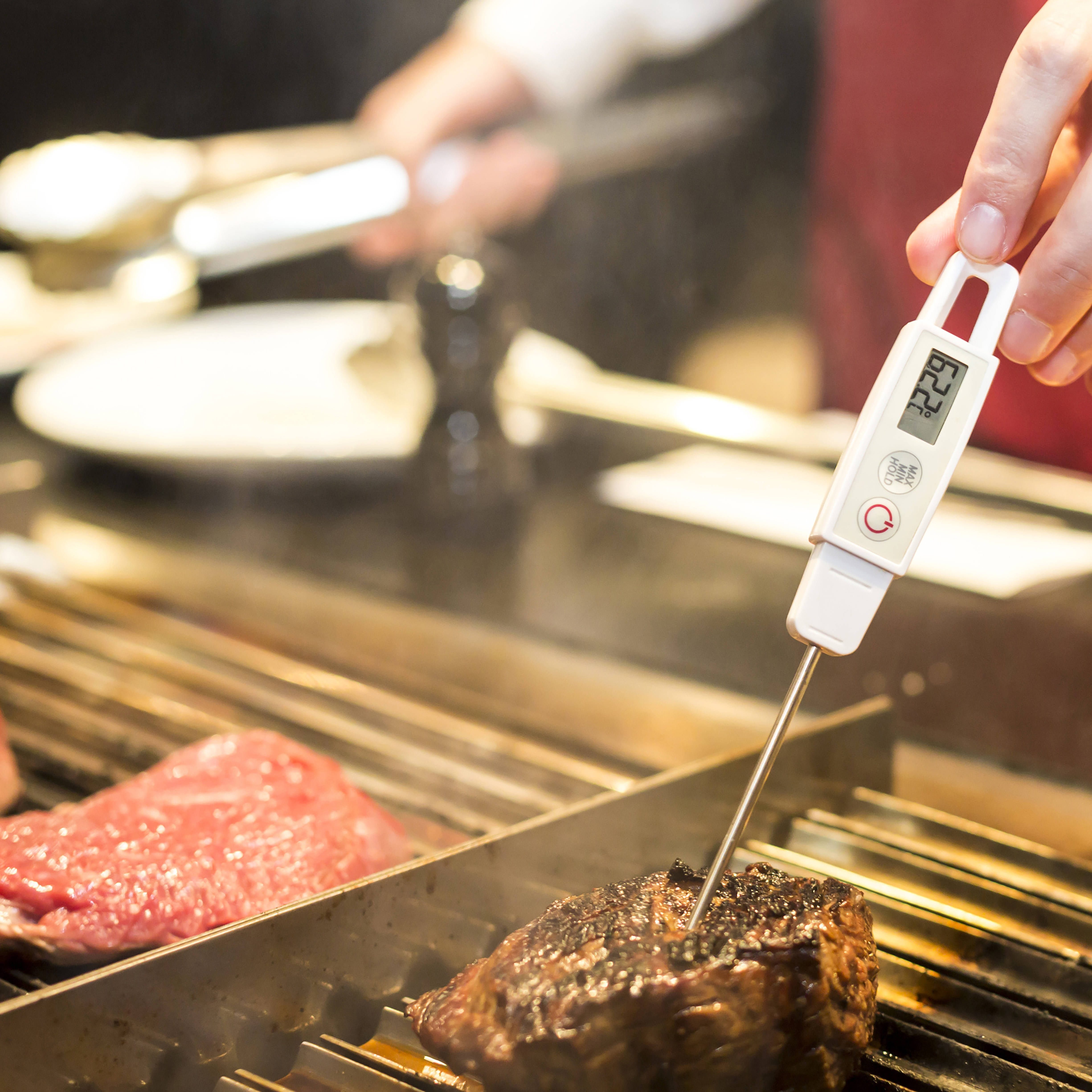 A cook checking the temperature of a filet with a digital thermometer