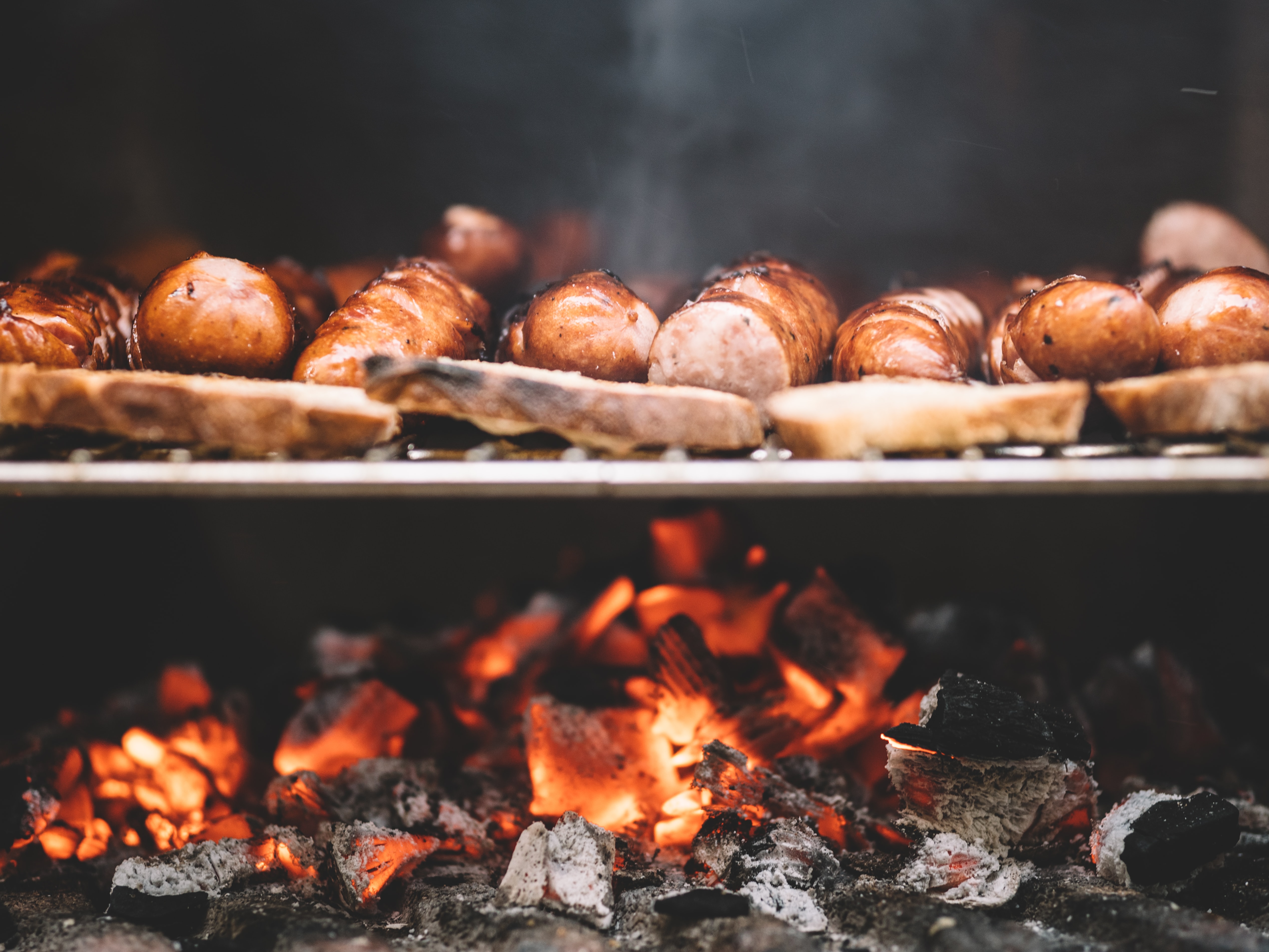 Sausages cooking over wood chips on a grill 