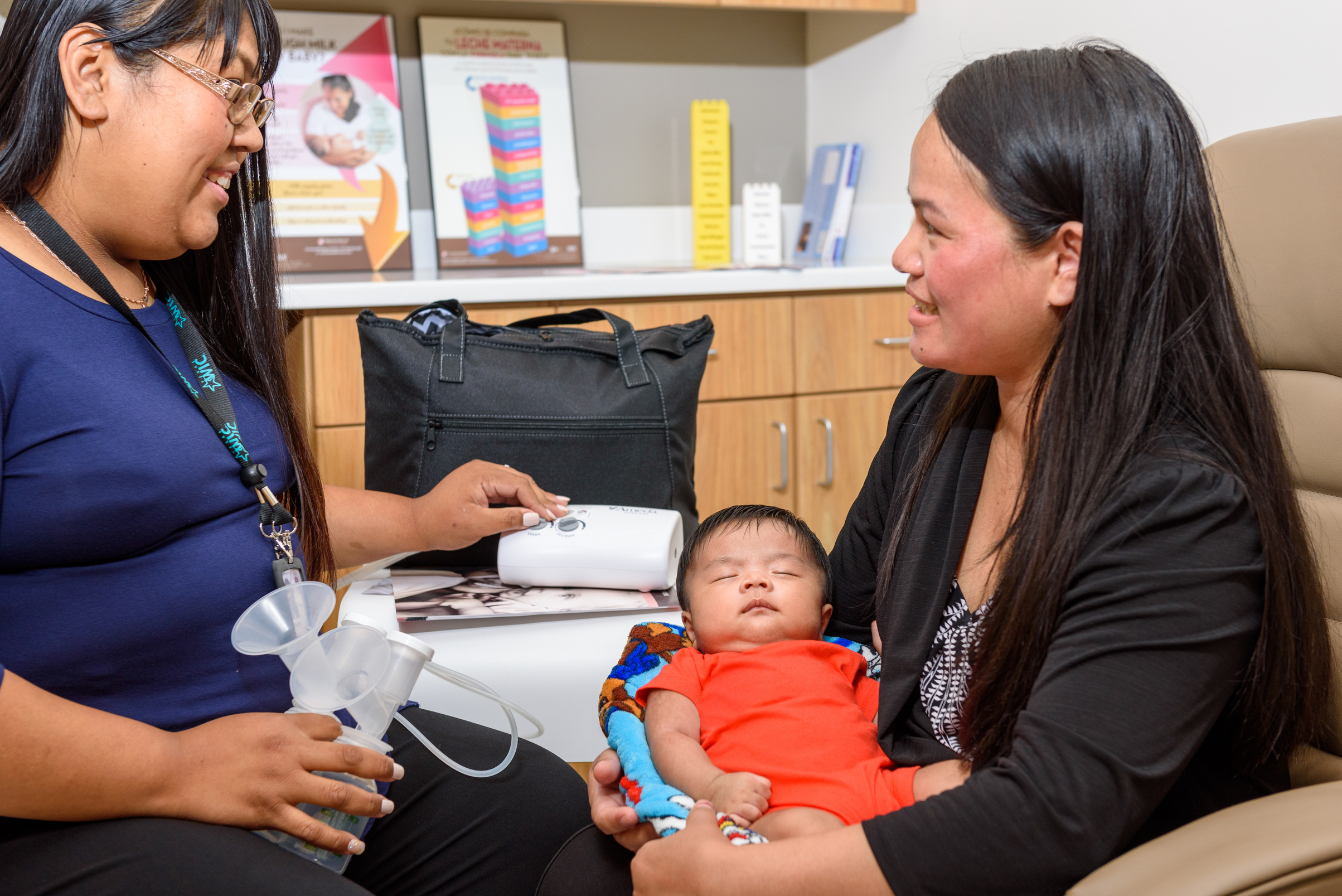 A WIC educator showing a breastfeeding pump to a client with an infant.